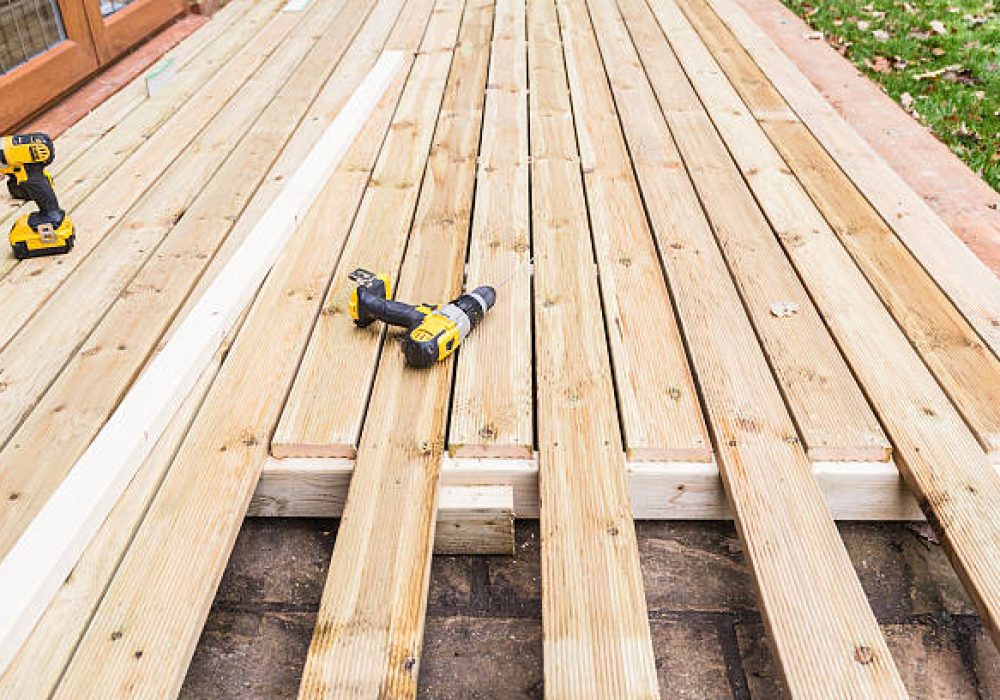 A new wooden, timber deck being constructed. it is partially completed. two drill can be seen on the decking.